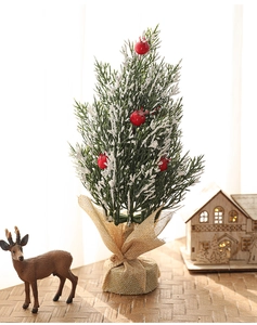 Detailed view of mini snow-flocked Christmas tree with red berries and burlap base