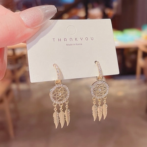 Detail of dreamcatcher gold earrings with sparkling crystals and metal feather drops
