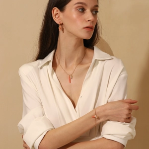 Model wearing a gold jewelry set featuring coral pendants and white flower details