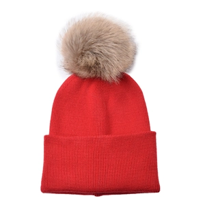 Detail of red cable knit kids beanie featuring a fluffy brown faux fur pom pom top