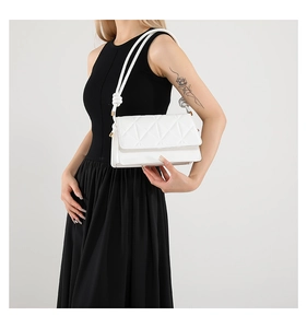 Close-up of white crossbody bag with geometric quilted pattern and knotted strap detail