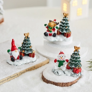 Miniature Christmas resin figurines with Santa and reindeer next to a small festive tree