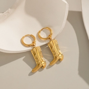 Detailed view of 18K gold plated stainless steel cowboy boot earrings on stone pedestal