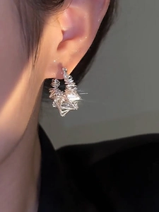 Detail of silver geometric hollow round hoop earring worn on a model ear