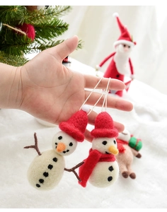Close-up of handmade wool felt snowman ornaments with red hats and hanging strings