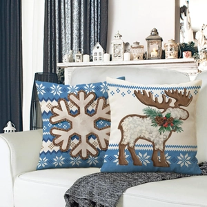 Blue Christmas linen pillow covers with snowflake and reindeer motifs on a white sofa