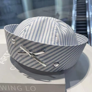 Detail of blue and white striped sailor hat with silver bow, pearl, and rhinestone