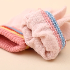 Détail du poignet en tricot rose avec rayures colorées montrant la texture de la laine
