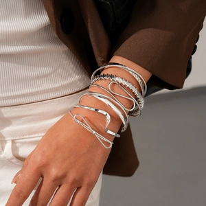 Détail de 6 bracelets géométriques argentés superposés portés élégamment au poignet
