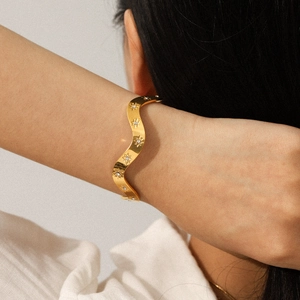 Détail d'un bracelet doré ondulé avec étoiles et zircons porté par un mannequin