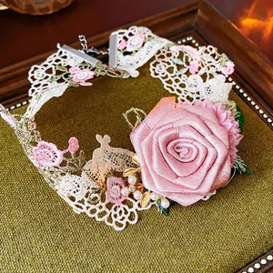 Pink satin rose fabric choker necklace with lace, pearls and gold leaves on green background