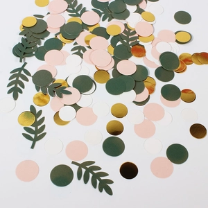 Detail von rosa, grünen und goldenen Konfetti-Blättern auf einer weißen Oberfläche
