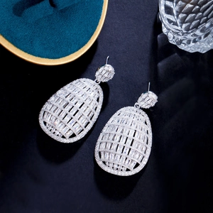 Macro shot of silver-tone teardrop earrings with full cubic zirconia stones on dark velvet