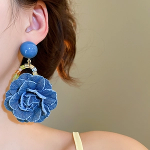 Gros plan de boucles d'oreilles roses en denim bleu avec perles sur un mannequin femme