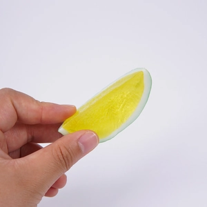 Realistic PVC lemon slice keychain held by hand for scale, featuring detailed fruit texture