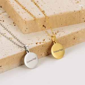Polished silver and gold Christmas Magic engraved disk necklaces on stone