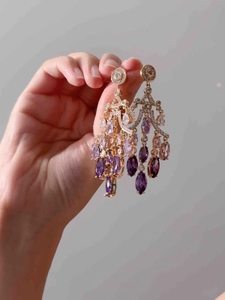 Detailed macro view of vintage gold chandelier earrings with purple zircon drop pendants