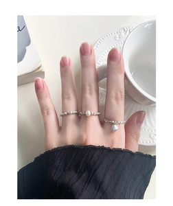 Close-up of S925 silver beaded rings featuring a pearl and heart pendant on hand