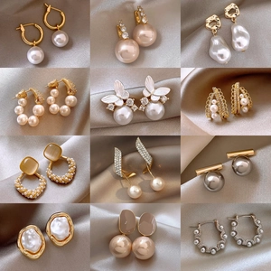 Elegantes Set aus Perlen und Blumenohrringen mit Vergoldung auf seidigem Hintergrund