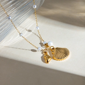 Détail de la chaîne perlée plaquée or 18k avec pendentifs coquillage et conque au soleil
