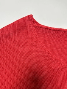 Detalle del cuello en V y la textura de punto fino de este suéter rojo de corte holgado