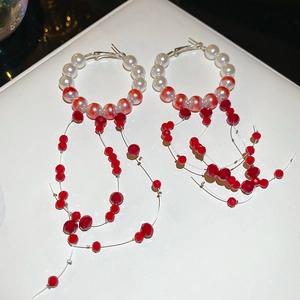 Detail of elegant red and white beaded tassel earrings with silver hooks and pearls