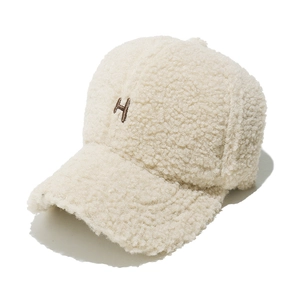 Détail d'une casquette en laine d'agneau crème avec broderie H et texture épaisse