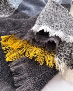 Macro shot of knitted texture and tassel details on a multi-color checkered winter scarf