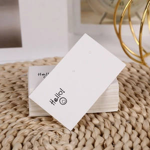 Close-up of white earring display cards with smile icon on a woven background