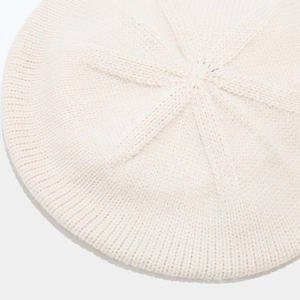 Makroansicht der cremefarbenen Strickbarette mit dicker Wollmischung und radialen Strickmustern