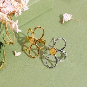 Détail d'une bague fleur ajourée réglable en finition or et argent avec centre texturé