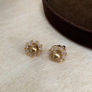 Detail of golden pearl stud earrings with sparkling cubic zirconia halo settings