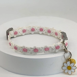 Detailed view of white lace cat collar with daisy embroidery and enamel floral pendant