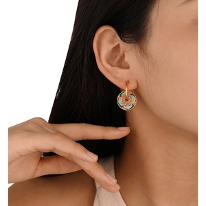 Ethnic style gold hoop earrings with red and blue enamel flower pendants on model