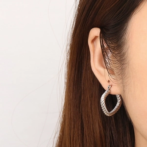 Silver twisted cable square hoop earrings worn on model's ear showing realistic fit