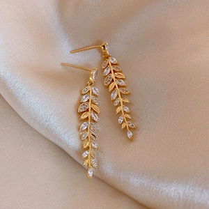 Luxurious gold wheat leaf drop earrings with marquise crystals on champagne velvet