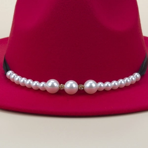 Close-up of rose red wool fedora featuring black ribbon and elegant pearl beadwork