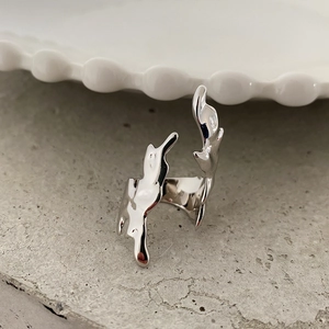 Detailed shot of silver flame ring with organic liquid texture on gray stone
