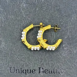Detail of vintage 18k gold C-shape bamboo earrings with pearls on a dark stone background