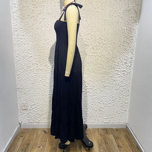 Detail of black tiered sleeveless dress featuring delicate shoulder tie-up bow accents