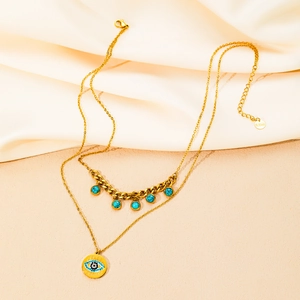 Dettaglio della collana a doppio strato in acciaio dorato con ciondolo occhio e perle blu