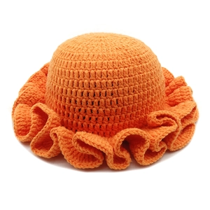 Detail showing hand-crocheted vibrant orange knit hat with wide ruffled brim and thick yarn