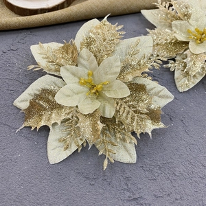 Champagne gold artificial Christmas flower with glitter on a textured dark background
