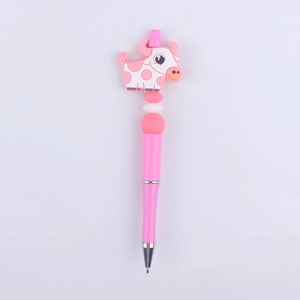 Detail of a pink plastic beaded pen featuring a cute silicone cartoon cow topper and silver ring