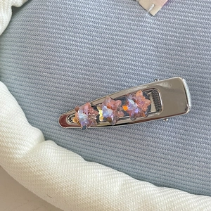 Close-up of silver metal hair clip with three pink heart-shaped crystal rhinestones