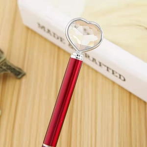 Elegant red metal ballpoint pen featuring a large sparkling heart diamond crystal top