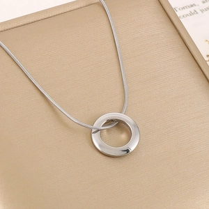 Detail of silver snake chain necklace with hollow circular pendant on decorative box