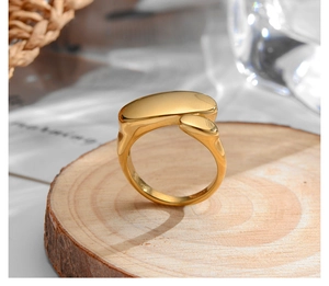 Detail view of a 18k gold plated stainless steel irregular oval ring on a wooden stand