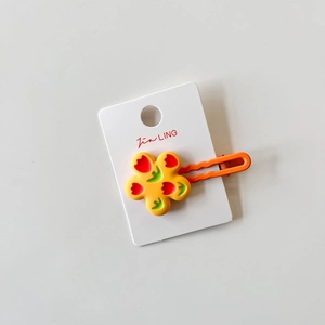 Detail of yellow flower hair clip with tulip pattern on orange matte finish metal