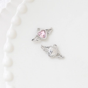 Detailed macro view of silver bow-knot pendants with pink heart stones for DIY jewelry